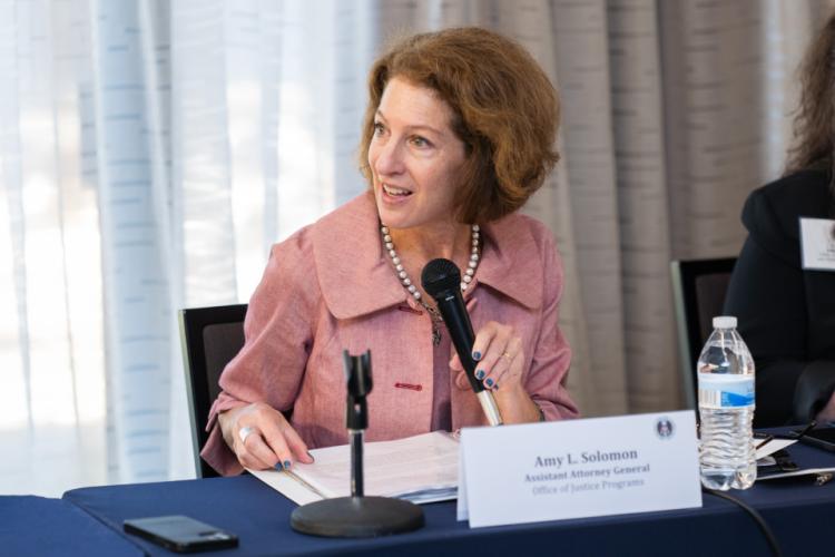Assistant Attorney General of the Office of Justice Programs Amy Solomon, speaking and holding the microphone