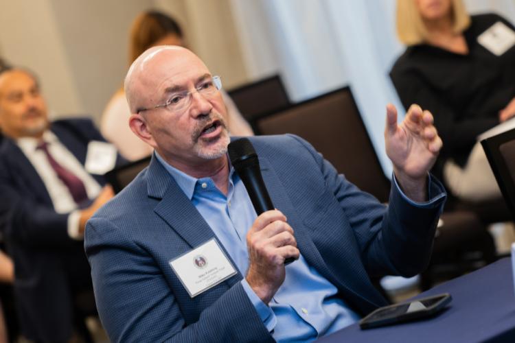 Dr. Mike Feinberg, President and Co-Founder, Texas School Venture Fund (TXSVF) and Career for All speaking and holding the microphone