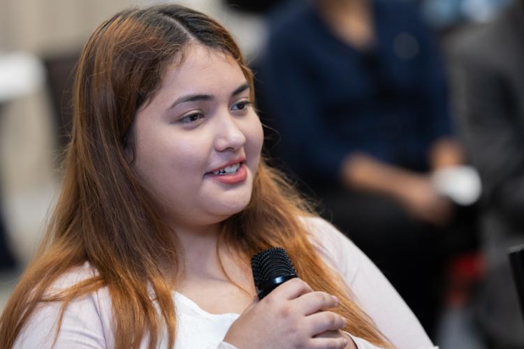 Alyssa, a student presenter, holding the microphone and smiling